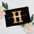 Custom black canvas makeup bag with gold letter monogram and stylish white cursive name text. - Letter H