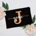 Detail view of the custom black canvas cosmetic bag featuring a bold gold letter and script name. - Letter J