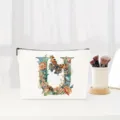 Close-up detail of the canvas makeup pouch featuring an elegant floral letter U and butterfly print. - Letter U