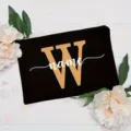 Detail view of custom black makeup pouch featuring a gold letter W and white name print. - Letter W