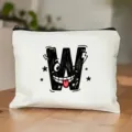 Detailopname van witte cosmetische tas met speelse zwarte W-letterprint op houten tafel. - Letter W Stijl