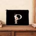 Close-up detail of the black cosmetic pouch featuring a custom gold letter P and floral print. - Letter P