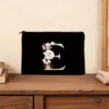 Black canvas cosmetic bag featuring a floral letter E design, elegant zipper clutch pouch. - Letter E