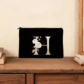 Black cosmetic bag with elegant gold letter H and floral design, perfect for daily use. - Letter H