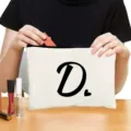 Weiße Kosmetiktasche aus Leinen mit schwarzem Buchstabe D Aufdruck und einem kleinen Herz. - Stil D