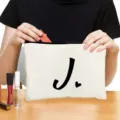 White canvas cosmetic bag with black letter J print, zipper pouch for travel makeup storage. - Style J