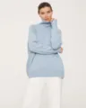 Close-up detail view of a stylish casual loose-fit light blue turtleneck knit sweater. - Light Denim Blue