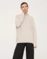 Detailed view of women's cozy high-neck knitted sweater featuring a relaxed fit. - Apricot