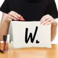 Detailed view of white canvas zipper cosmetic bag featuring custom black letter W and heart print. - Style W