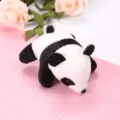 Detailed close-up of a cute black and white plush panda toy resting on a pink grid mat. - Style 4 Panda Brooch