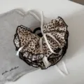 Primo piano di un fermaglio per capelli leopardato vintage con fiocchi bianchi e bordo nero. - Leopardo Chiaro alla Moda - Molla con Volants