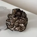 Primo piano di un elegante fermacapelli con stampa leopardata e bordo nero per acconciature. - Leopardo Chiaro alla Moda - Molla Floreale