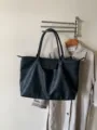 Schwarze Pendler-Tasche Detailansicht mit grossem Fassungsvermoegen, stabilen Griffen und Klappe. - Schwarz