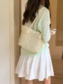 Detail shot of a soft woven hollow tote bag carried on shoulder, showcasing the elegant summer style. - White
