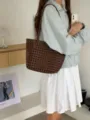 Vue détaillée du sac porté épaule en cuir tressé marron foncé, montrant sa texture souple. - Café