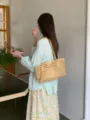 Vista dettagliata di una borsa a spalla intrecciata cava chic, ideale per le vacanze estive. - Giallo