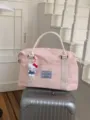 Close-up of a pink canvas travel duffel bag with woven handles and cute plush pendant decoration. - Pink Without Charm