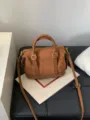 Detail view of a retro brown suede bowling handbag with metal hardware and dual top handles. - Matte Brown