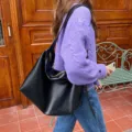 Detail view of the black slouchy minimalist shoulder bag showcasing soft PU leather texture. - Black