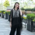 Detailansicht der Outdoor-Szene zeigt den eleganten schwarzen Spitzen-Kimono-Cardigan mit Fransen. - Schwarz