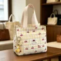 Detailed view of the yellow plaid cosmetic bag featuring cute cherry prints and handle. - Yellow