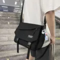 Detail view of stylish black canvas messenger bag with astronaut keychain for daily commute. - Single Bag Without Pendant / Black