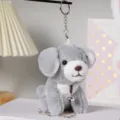 Primo piano del simpatico portachiavi con cagnolino in peluche grigio e campanello di metallo. - Cerchio / Grigio / 12cm