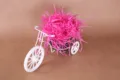 Felroze opvulmateriaal voor geschenkdozen, gepresenteerd met een wit ijzeren driewielermodel. - Rozerood