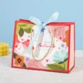 Rode cadeautas van papier met bloemen- en vogelpatroon, blauwe strik en gouden handgrepen. - Klein (18x10x16cm) / Roze Achtergrond Blauwe Lint