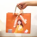 Cadeautas voor de dag van de leraren, oranje papierverpakking met strik en mooi ontwerpje. - S / Geel