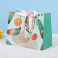 Decoratieve groene papieren geschenkzak met roze strik en handgrepen voor feest - Blauwe Achtergrond Roze Lint