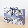 Decoratieve papieren cadeautas met bloemenprint, elegante blauwe strik en handige koorden. - 0115 Gouden & Donkerblauwe Lint / S
