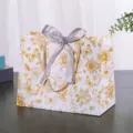 Bloemige geschenkpapier tas met strik, elegante verpakking voor cadeaus en kledingstukken - Kleine Maat 18x16x10cm / Goud Bloemen met Tekst (Zilveren Lint)