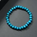 Primer plano detalle de pulsera de cuentas de madera azul, textura lisa y diseño. - Azul cielo