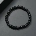 Vista detallada de la pulsera de cuentas de madera negra, textura lisa, elástico, estilo minimalista. - Negro
