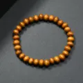 Primer plano de pulsera de cuentas de madera con textura redonda lisa y cuerda elástica. - Tostado