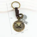 Vintage bronze owl keychain with leather strap and metal pendant, retro style accessory. - Coffee