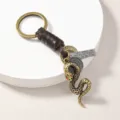 Close-up detail of vintage metal snake keychain with leather wrap and engraved metal tag. - Snake