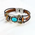 Primer plano de una pulsera de cuero multicapa con piedra turquesa ovalada y cierre de acero. - Turquesa Ovalada / Marrón