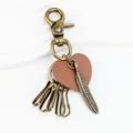Primer plano del llavero de corazón con pluma vintage, acabado metálico delicado. - Bronce