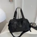Detailed view of black lightweight travel duffel bag, showing durable fabric and sturdy straps. - Black