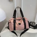 Detailed view of large capacity pink travel duffel bag with black straps for gym and sports. - Pink