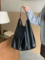 Detail shot of a casual black PU leather tote bag with a small attached pouch in hand. - Black