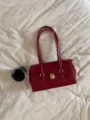 Red patent leather shoulder bag with gold-tone lock detail and dual straps for women. - Red