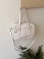 White Japanese JK uniform bag detail showing dual straps, shoulder strap and clean design. - Off White