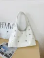 Vista dettagliata della borsa in pelle bianca con eleganti occhielli metallici e comoda tracolla. - Bianco