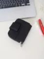 Vista dettagliata di una mini pochette nera con bottone automatico e gancio in metallo. - Nero