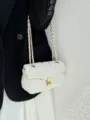 Primo piano dettagliato di una borsa a tracolla in pelle trapuntata bianca con catena dorata. - Bianco