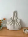 Dettaglio della elegante borsa a sacco écru con morbide pieghe e stile casual. - Bianco