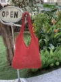 Dettaglio ravvicinato della borsa in morbido tessuto rosso nel giardino all'aperto. - Rosso